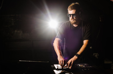 DJ plays on a mixer in the club on black background