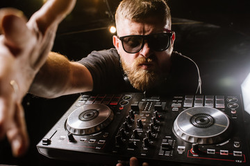 DJ plays on a mixer in the club on black background