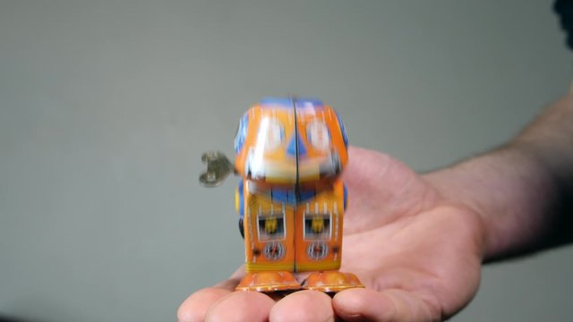 4K man holding vintage tin wind up walking robot toy , kids toy. Colourful Toy