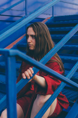 Young woman in red mantle posing on blue background. Millennial concept.
