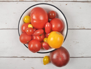 Tomaten in Emailschale auf verwittertem Holz