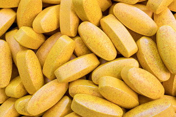 Turmeric health food supplement tablets yellow background