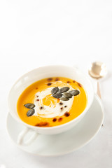 Seasonal food.Pumpkin soups. Soup decorated with cream sauce and pumpkin seeds. White background .Autumn foliage.Autumn.