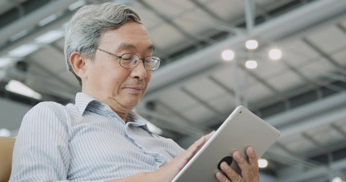 Senior man using tablet on the flight timetable background in airport.