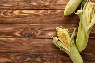 top view of uncooked sweet corn on wooden surface