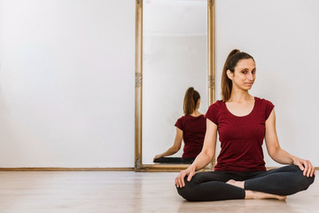 Yoga instructor sitting in lotus pose in yoga studio