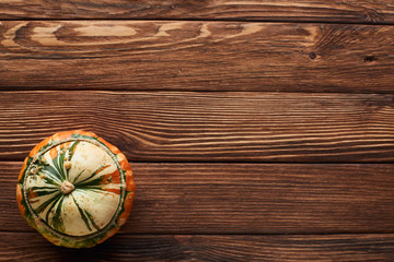 Fototapeta na wymiar top view of small ripe pumpkin on brown wooden surface with copy space