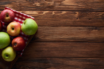 top view of checkered tablecloth with fresh apples on wooden surface with copy space