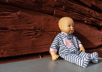 Forgotten doll in the background of red, old, wooden wall. The texture of the old wood. Photo for background, there is a place for text.