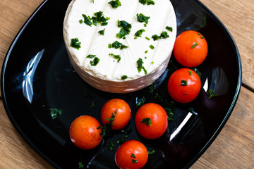 Breakfast food, cheese and cherry tomatoes on dish, on a rustic wooden plank board table background.