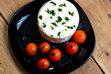 Breakfast food, cheese and cherry tomatoes on dish, on a rustic wooden plank board table background.