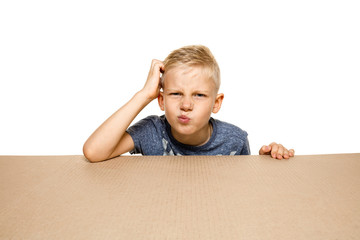 Cute and upset little boy opening the biggest postal package. Disappointed young male model on top of cardboard box looking inside. Gift, present, delivery, shipment, sales, black friday concept.