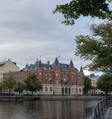 Fototapeta premium Sweden. Red brick building by the river. Cloudy day in Orebro. Travel photo.