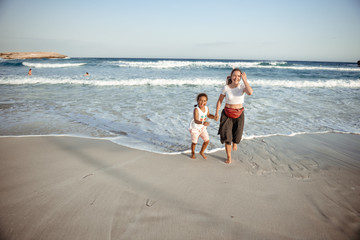 Family walking on the evening beach during sunset. Child with mom.