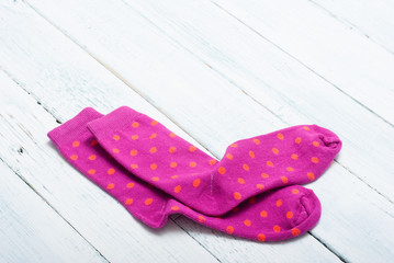 pair of magenta socks with orange dots on white wooden