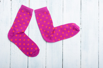 pair of magenta socks with orange dots on white wooden