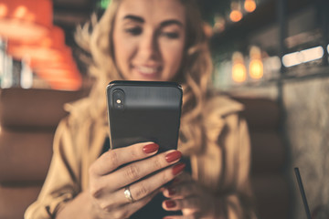 Young charming woman calling with cell telephone while sitting alone in coffee shop during free time, attractive female with cute smile having talking conversation with mobile phone