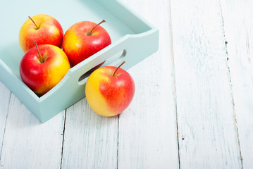 apples at blue tray, white wood table