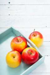apples at blue tray, white wood table