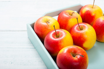 apples at blue tray, white wood table