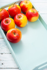 apples at blue tray, white wood table