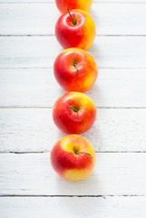 apple fruits in a row, white wooden table background