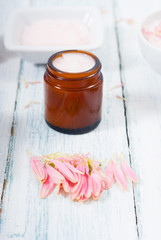 beauty product samples, cosmetic cream, bath salt, liquid soap and pink flower, white wood table