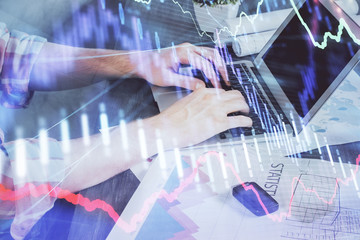 Double exposure of stock graph with businessman typing on computer in office on background. Concept...