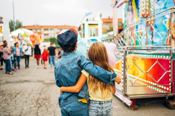 Boy and girl walk together hugging on the Boy and girl walk together hugging on the amusement park