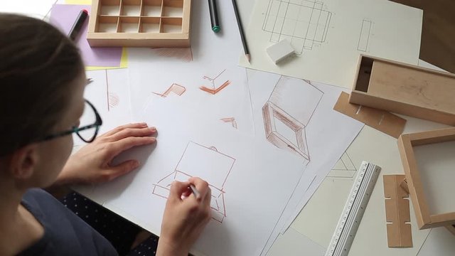 Woman designer draws a sketch of paper packaging. Development of a cardboard box layout. 