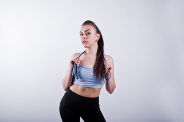 Cheerful attractive young fitness woman in top and black leggings with jump rope isolated over white background.