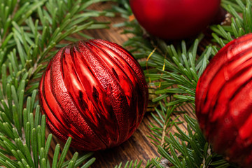 Fur spruce pine coniferous branches, sparkling shiny toys balls on the brown brushed wooden background