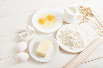 flour, eggs, butter and milk on a white wooden background, ingredients for baking
