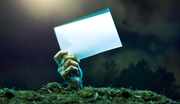Image of zombie hands with empty sheet of paper sticking out