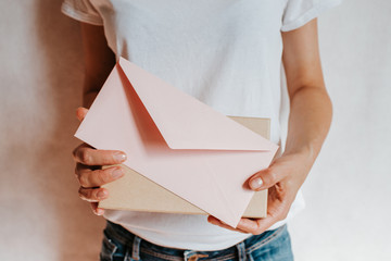 Woman holds in hand paper envelope and box. New mail, message. Postal service. Young girl want send or receive letter and package. Blank envelope, empty space. People communication. Envelope closeup