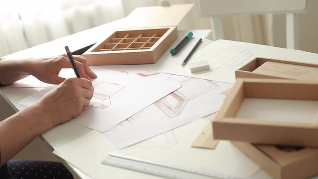 Woman designer draws a sketch of paper packaging. Development of a cardboard box layout. 
