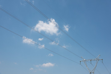 A beautiful large steel high voltage electric tower stands on a background of blue sky