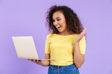 Image of excited african american woman holding laptop computer