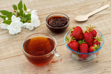 Glass cup of tea, strawberries with white jasmine flowers