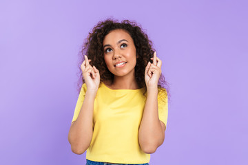 Image of pretty african american woman keeping fingers crossed