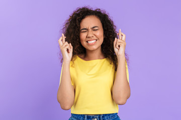 Image of cheerful african american woman keeping fingers crossed