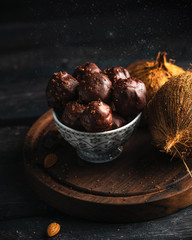 homemade chocolates and coconuts on a dark wooden backdrop, copy space