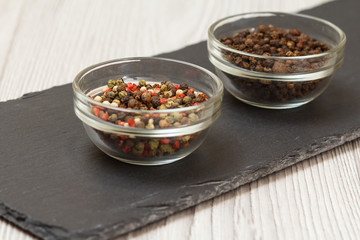 Allspice berries in bowls on stone cutting board.