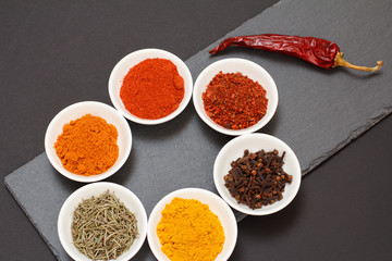 Various ground spices and herbs on stone cutting board.