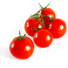 Red juicy cherry tomatoes with green tails lying on a white background