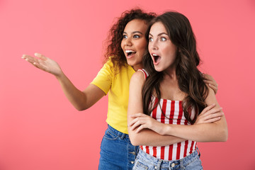 Image of excited multinational girls wondering while looking aside at copyspace