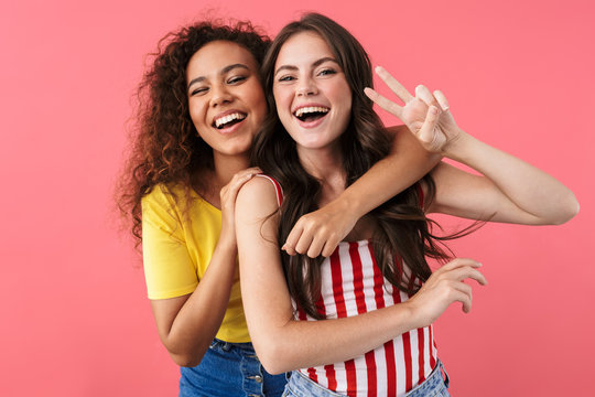 Image of happy multinational girls hugging and showing peace sign