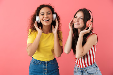 Image of amazed multinational girls listening to music with headphones