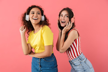 Image of cheerful multinational girls listening to music with headphones