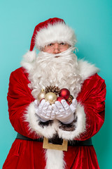 Santa Claus holding handful of Christmas tree decorations